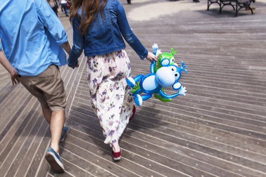 Cropped rear view of couple holding hands on boardwalk