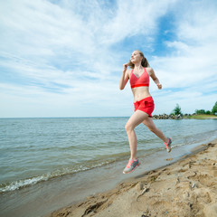 Young lady running at the sunny summer sand beach. Workout.  Jog