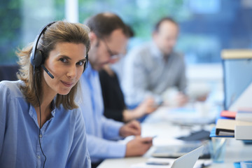 Woman wearing telephone headset in office
