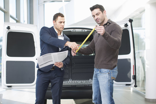 Customer and salesman checking van measurements in car dealership