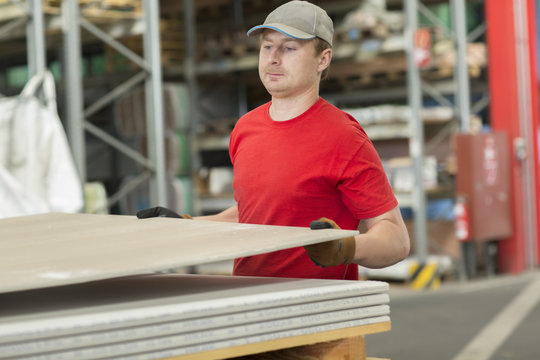 Worker lifting boards in hardware store warehouse