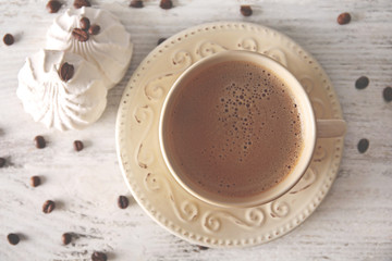 Cup of coffee with beans and zephyr on wooden table, top view