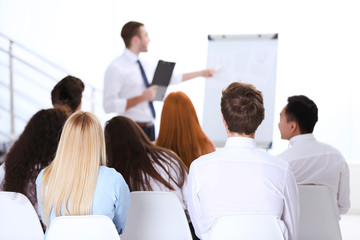 Fototapeta premium Business presentation and training session with diverse audience learning from professional speaker, a professional speaker addresses the group, pointing to a whiteboard during the corporate learning