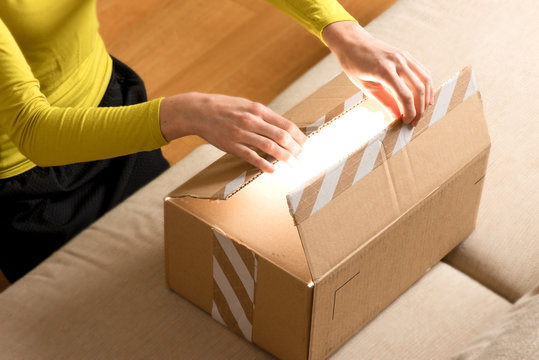 woman opening cardboard box at home, online shopping