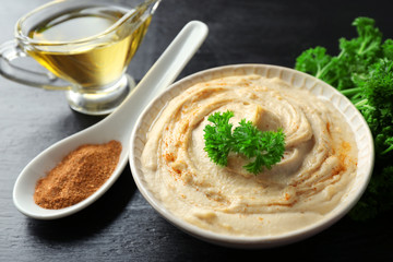 Ceramic bowl of tasty hummus with parsley on table, close up