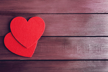 Red felt hearts on purple wooden background