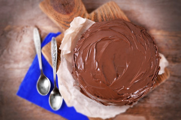 Chocolate cake with two spoons and blue tablecloth on a wooden boards background