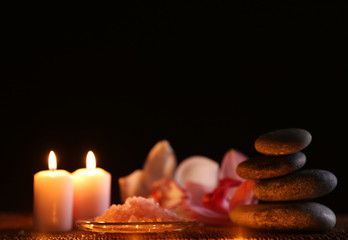 Spa still life with stones, candles and flowers in water on black background