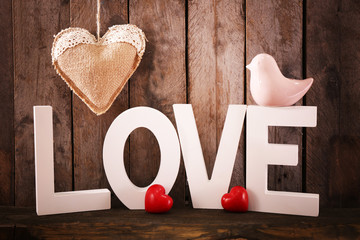 Love word with white letters and hearts on wooden background