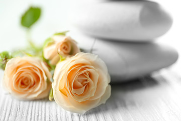 Beautiful roses with spa stones on white wooden table