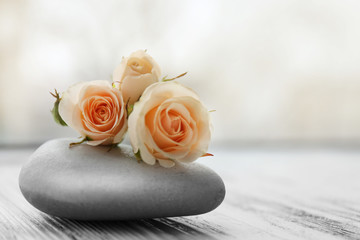 Beautiful roses with spa stone on white wooden table