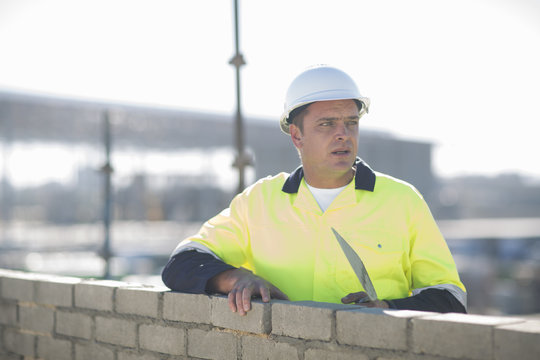 Brick layer using trowel on construction site wall