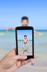 Tourist holding smart phone to take picture during vacation capt