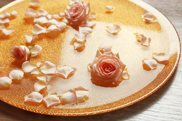 Pink rose petals in golden bowl with water on wooden background