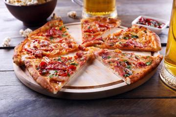 Sliced pizza and glass of beer on wooden table, close up