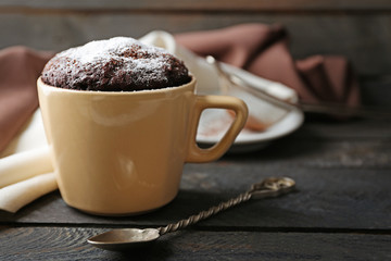 Chocolate fondant cake in cup on wooden table closeup