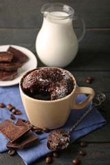 Chocolate fondant cake in cup on wooden background