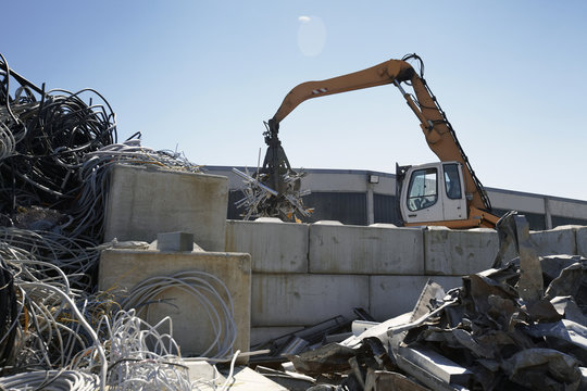 Grapple handler sorting and moving aluminium in scrap yard