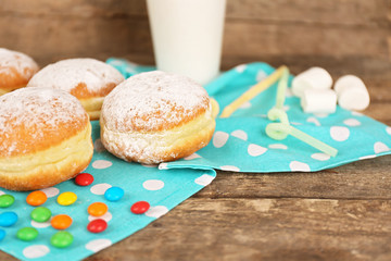 Delicious sugary donuts with blue napkin on wooden background