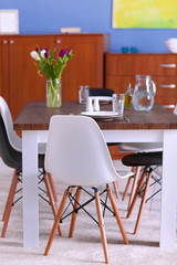 Modern living room. Furniture set with table and chairs. Bouquet of beautiful white and purple tulips on the table