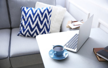 Modern interior. Comfortable workplace. Table with laptop and cup of coffee on it