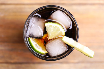 Cocktail with lime slices and ice blocks on wooden table, top view