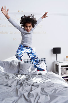 Boy jumping on bed with arms up