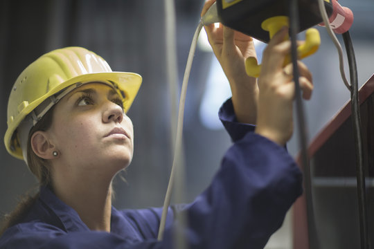 Female engineer checking valves and cables in factory