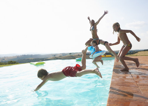 Five people jumping into swimming pool