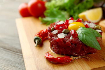 Beef tartare served on a wooden board, close up