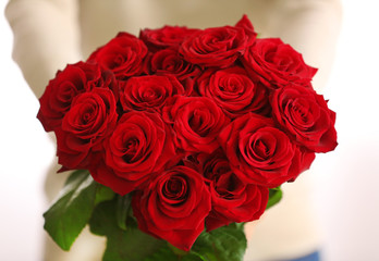 Woman with beautiful bouquet of red roses closeup