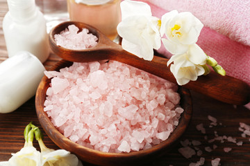 Obraz na płótnie Canvas Spa composition with sea salt in a bowl, soft towels and flowers on wooden background, close up