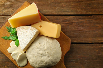 Fresh Italian pizza dough with different kinds of cheese on wooden background