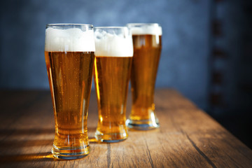 Three glasses of light beer on wooden table