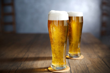 Two glasses of light beer on wooden table