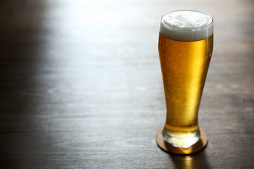 Glass of light beer on wooden table