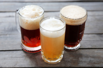 Glass mugs with different sorts of craft beer on wooden table