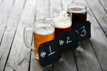 Glass mugs with different sorts of craft beer and numbering on wooden table