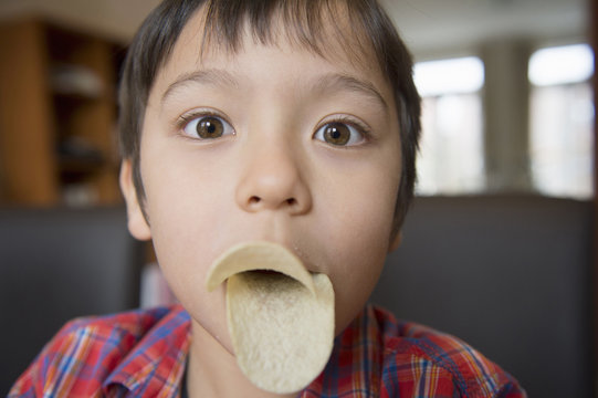 Boy imitating bird beak with crisps