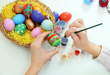 Fototapeta na wymiar Female hands painting Easter egg at table indoors