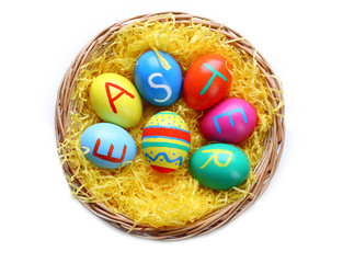 Fototapeta na wymiar Colorful Easter eggs in wicker nest isolated on white