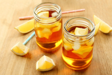 Jar of ice lemon tea with straw on wooden table