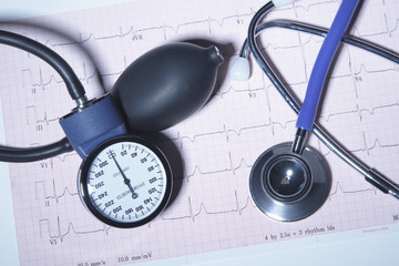 Acoustic stethoscope and blood pressure gauge on an electrocardiogram printout