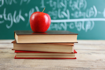 Few books with red apple on table