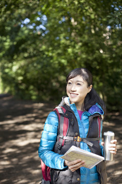 Young female hiker with map and flask