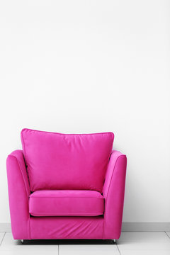Pink armchair on white wall background