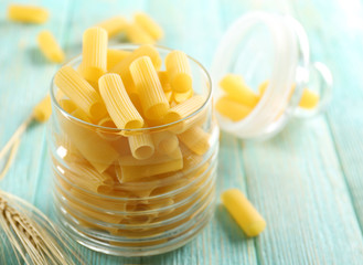 Raw pasta in glass jar on wooden table closeup