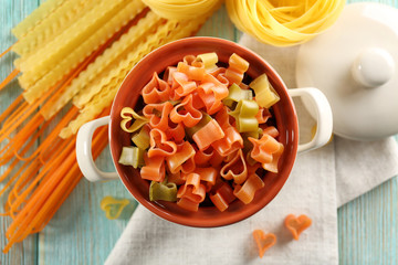 Different types of pasta on wooden table, top view