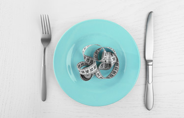 Plate and measuring tape on white table background