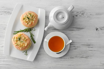 Tea with cakes on wooden background, top view